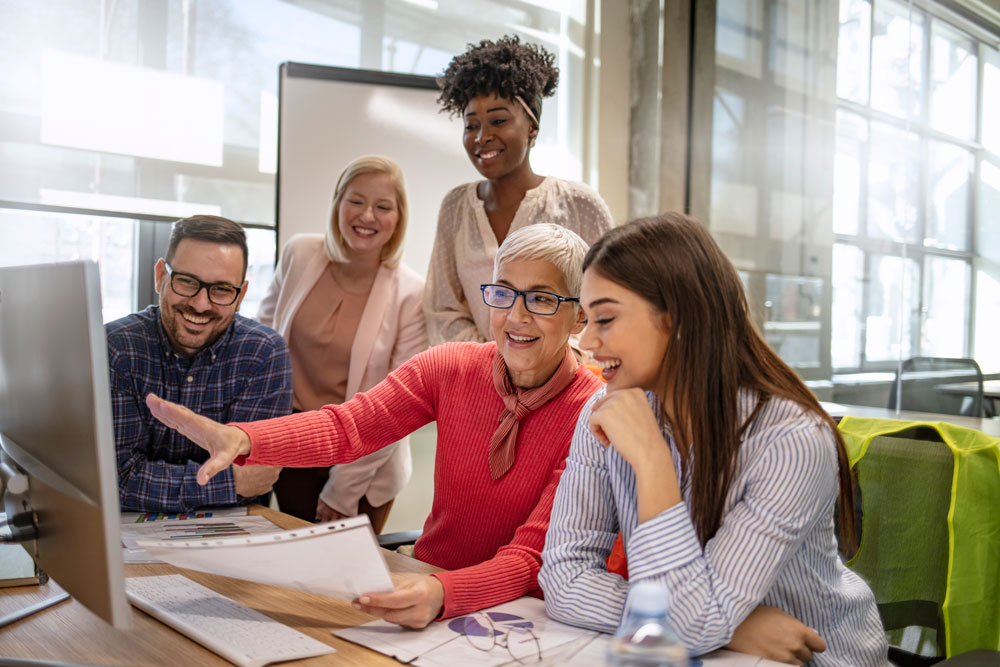 Female school business manager discussing work on a computer screen with her team