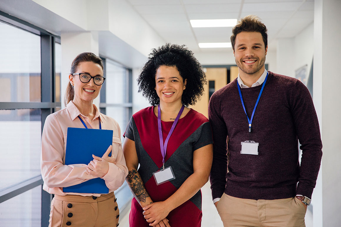 Two female and one male senior school staff standing in a school corridor